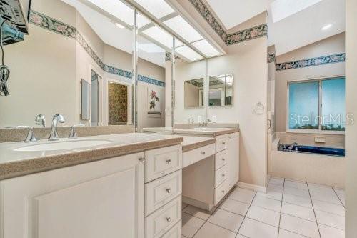 bathroom with tile patterned flooring, lofted ceiling, a tub, and double sink vanity