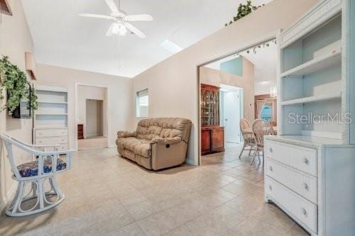 living room with built in features, light tile patterned floors, and ceiling fan