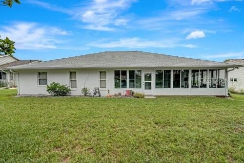 back of house with a sunroom and a lawn