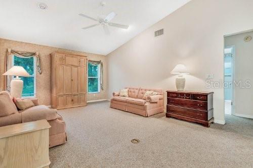 living area with high vaulted ceiling, light carpet, and ceiling fan