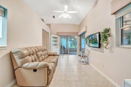 tiled living room with ceiling fan and lofted ceiling