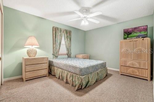 bedroom featuring carpet flooring, a textured ceiling, and ceiling fan