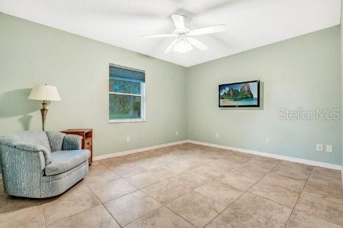 living area with ceiling fan and light tile patterned floors