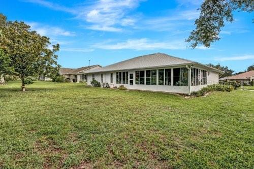 back of property with a sunroom and a lawn