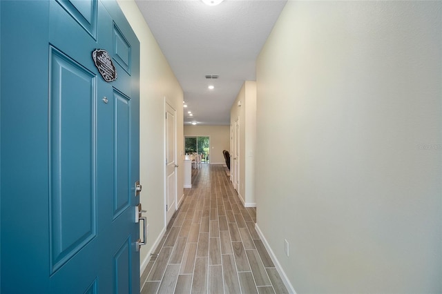 corridor featuring light wood-type flooring and a textured ceiling