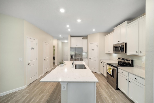 kitchen featuring appliances with stainless steel finishes, white cabinetry, a kitchen island with sink, and sink