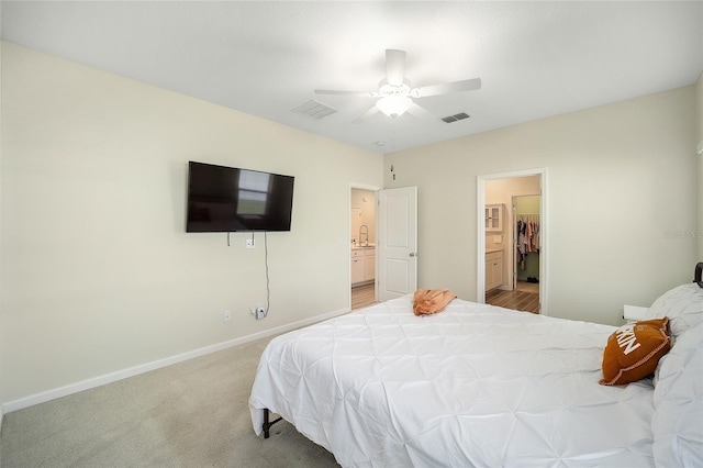 bedroom featuring connected bathroom, ceiling fan, sink, and light carpet