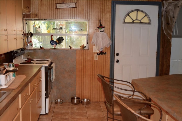 kitchen featuring light tile patterned floors, range with electric cooktop, and wooden walls