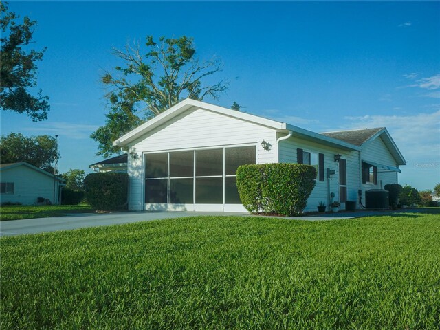 view of front of home with a sunroom, central AC unit, and a front lawn