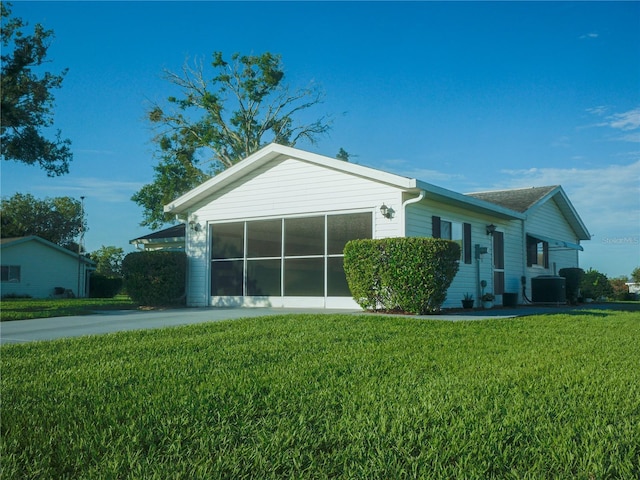 view of front of house with a garage, cooling unit, and a front lawn