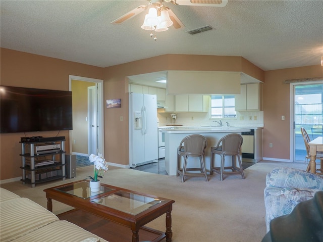 living room featuring sink, light colored carpet, a textured ceiling, and ceiling fan