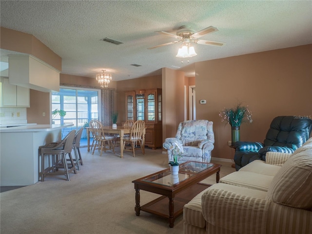 carpeted living room with ceiling fan with notable chandelier and a textured ceiling