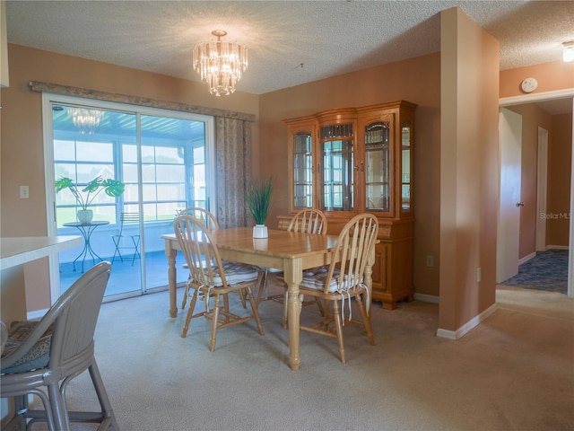 dining area featuring an inviting chandelier, light colored carpet, and a textured ceiling