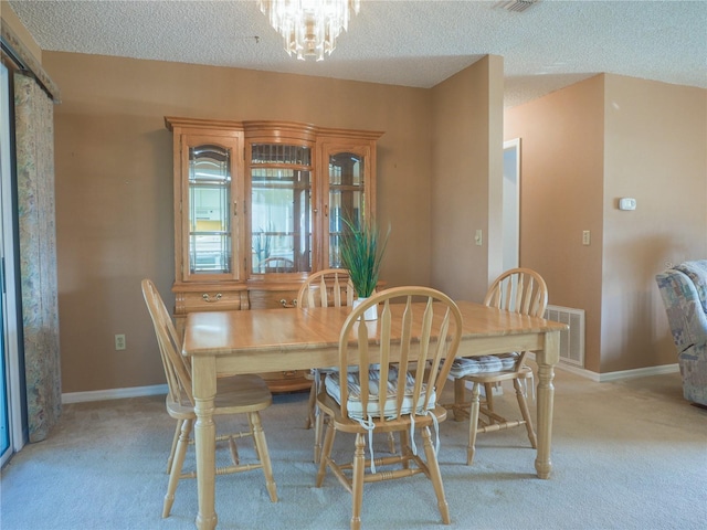 dining space featuring light colored carpet, a notable chandelier, and a textured ceiling