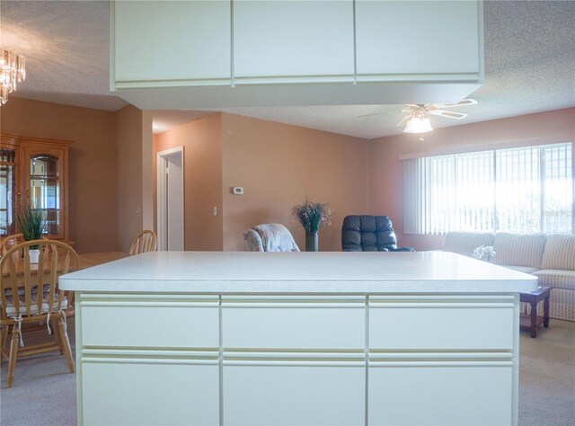 kitchen with ceiling fan, light carpet, and a textured ceiling