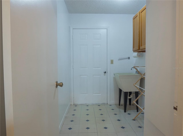 laundry area with cabinets and a textured ceiling