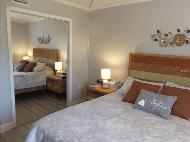 bedroom with hardwood / wood-style flooring, ornamental molding, and a closet