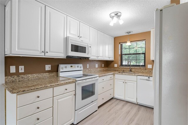 kitchen with pendant lighting, sink, white appliances, white cabinetry, and light wood-type flooring