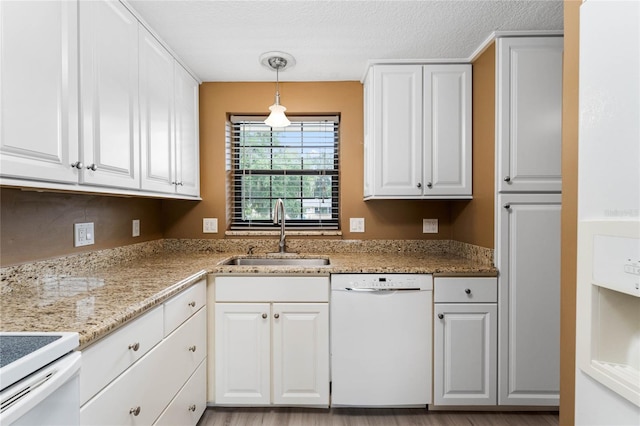 kitchen with hanging light fixtures, dishwasher, sink, and white cabinetry