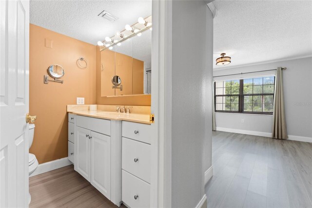 bathroom featuring vanity, a textured ceiling, wood-type flooring, and toilet