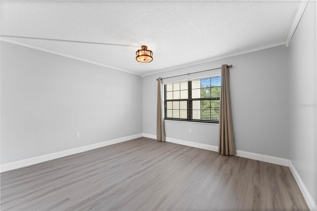 empty room featuring ornamental molding, a textured ceiling, and light wood-type flooring