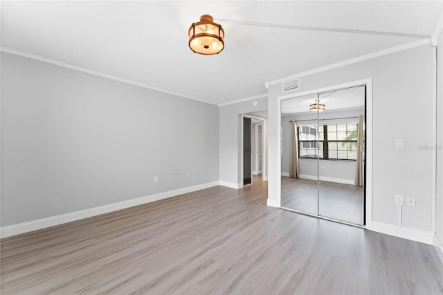 unfurnished bedroom featuring crown molding, light wood-type flooring, and a closet