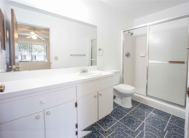 bathroom with a shower with shower door, toilet, tile patterned floors, vanity, and ceiling fan