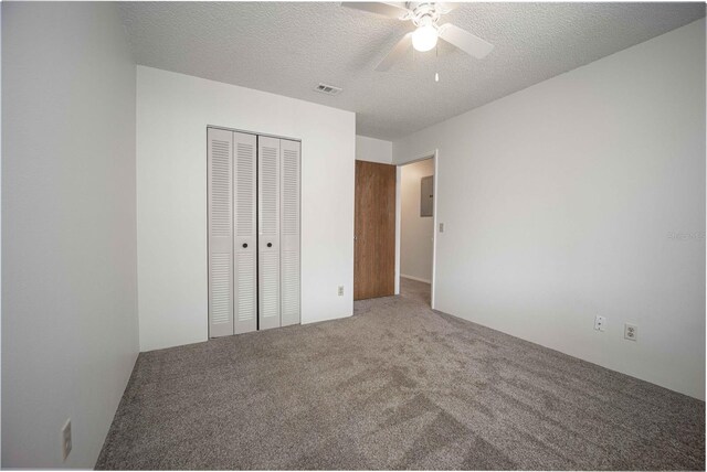 unfurnished bedroom with a textured ceiling, a closet, carpet, and ceiling fan