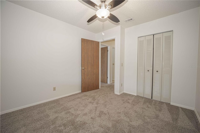 unfurnished bedroom featuring a textured ceiling, a closet, carpet floors, and ceiling fan