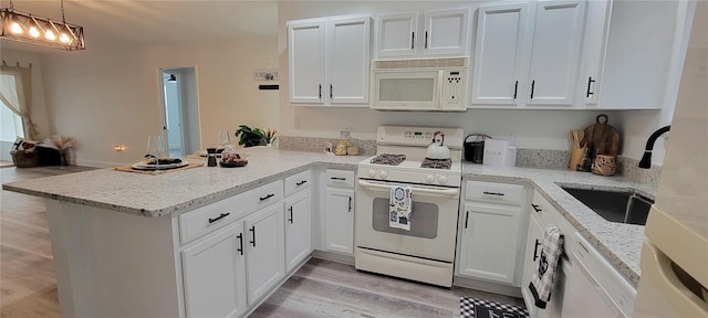 kitchen with white appliances, pendant lighting, white cabinetry, kitchen peninsula, and light wood-type flooring