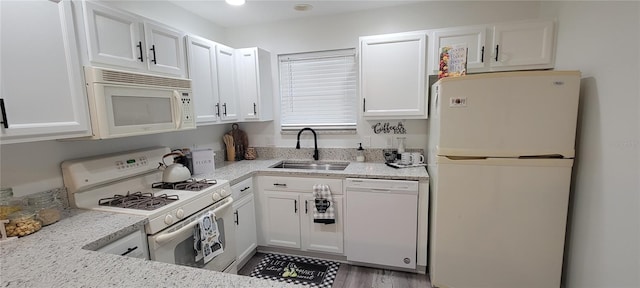 kitchen with sink, white cabinets, light stone counters, and white appliances