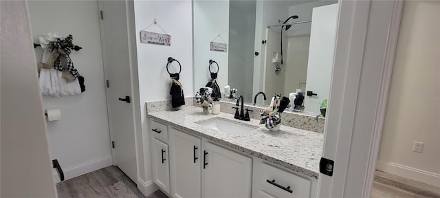 bathroom featuring walk in shower, vanity, and hardwood / wood-style flooring