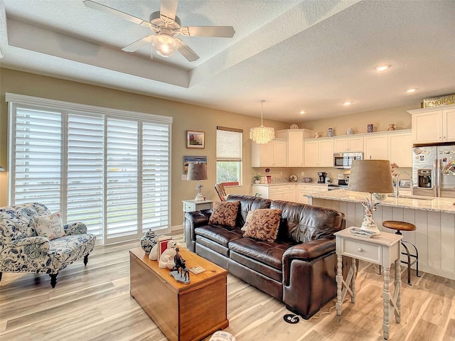 living room with light hardwood / wood-style floors, a textured ceiling, and ceiling fan