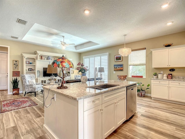 kitchen featuring sink, light hardwood / wood-style floors, stainless steel dishwasher, ceiling fan with notable chandelier, and a raised ceiling