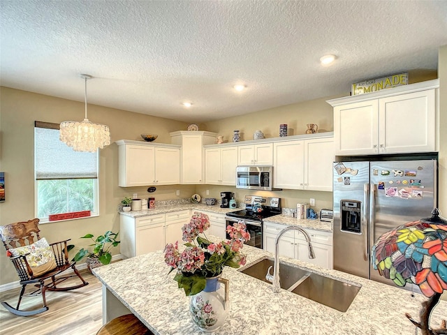 kitchen with sink, light stone counters, stainless steel appliances, and light hardwood / wood-style floors