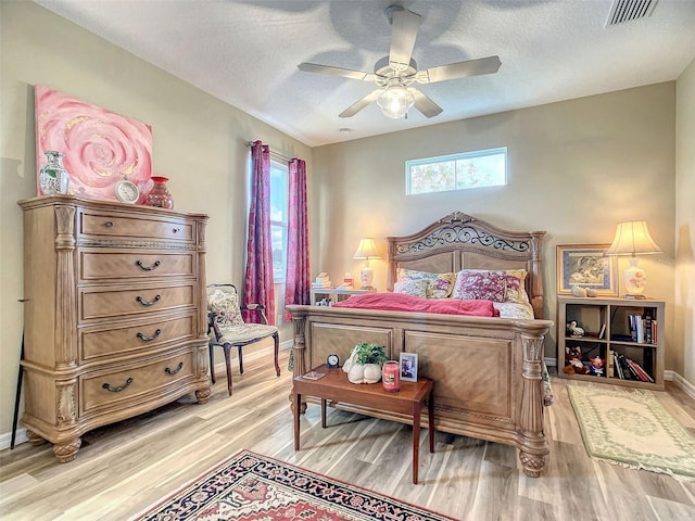 bedroom featuring light hardwood / wood-style flooring, a textured ceiling, and ceiling fan