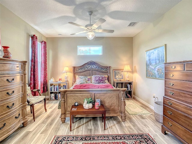 bedroom with light hardwood / wood-style flooring, a textured ceiling, and ceiling fan