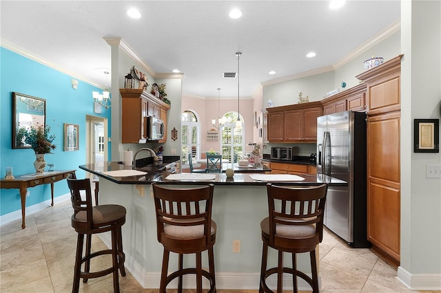 kitchen with a breakfast bar, decorative light fixtures, ornamental molding, appliances with stainless steel finishes, and kitchen peninsula