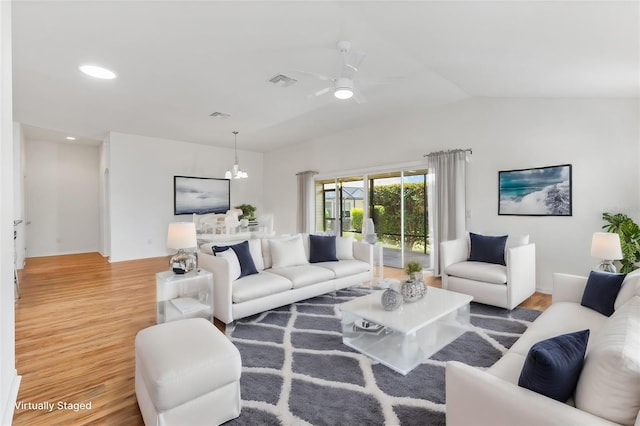 living room featuring hardwood / wood-style floors, ceiling fan with notable chandelier, and lofted ceiling