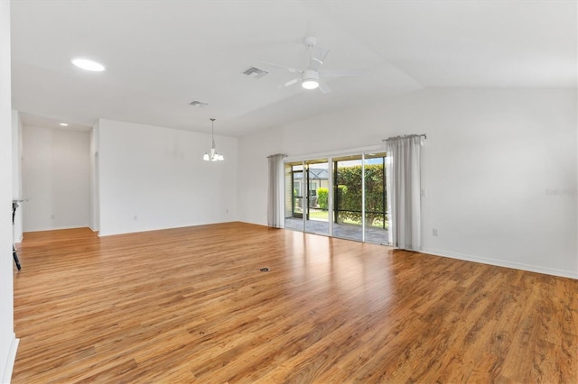 spare room featuring lofted ceiling, ceiling fan with notable chandelier, and light wood-type flooring