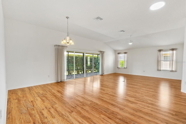 unfurnished room featuring ceiling fan with notable chandelier, light hardwood / wood-style floors, plenty of natural light, and lofted ceiling