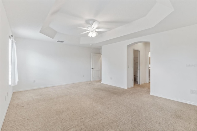 carpeted spare room featuring a tray ceiling and ceiling fan