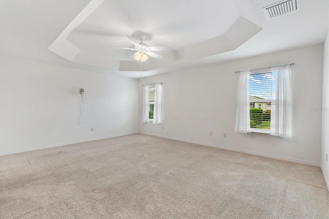 carpeted spare room with a tray ceiling and ceiling fan