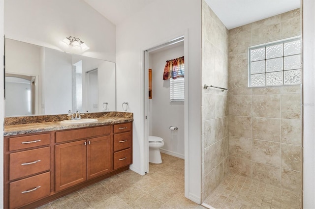 bathroom with vanity, toilet, and a tile shower