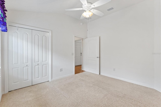 unfurnished bedroom featuring ceiling fan, a closet, light colored carpet, and vaulted ceiling