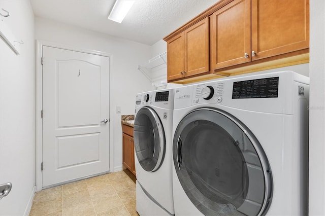 washroom with cabinets, independent washer and dryer, and a textured ceiling