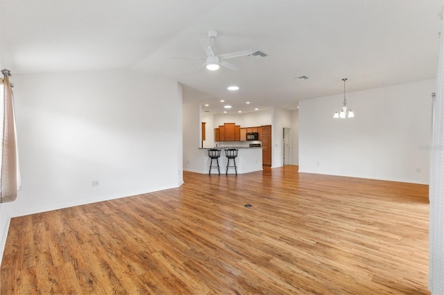 unfurnished living room featuring ceiling fan with notable chandelier, light wood-type flooring, and lofted ceiling