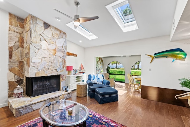 playroom featuring hardwood / wood-style floors, ceiling fan, a stone fireplace, and lofted ceiling with skylight