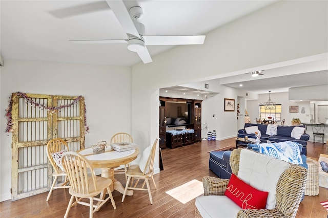 dining space with ceiling fan with notable chandelier and hardwood / wood-style flooring