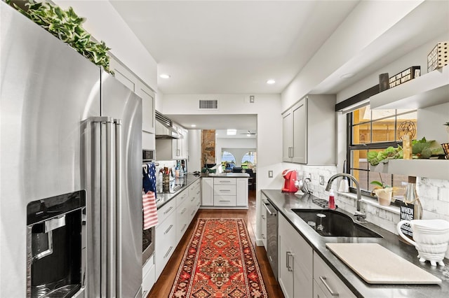 kitchen with sink, backsplash, white cabinetry, stainless steel appliances, and dark wood-type flooring